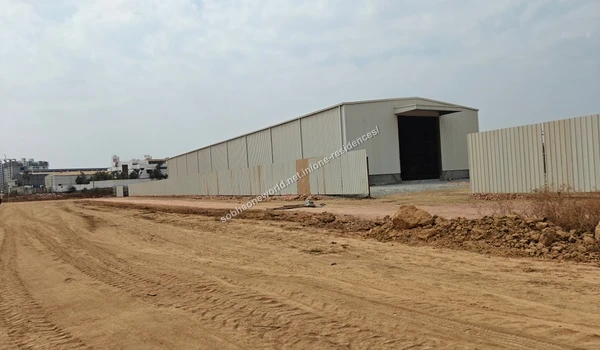 Wide view of the large warehouse style shed under construction at the Sobha One Residences property with a cleared dirt pathway