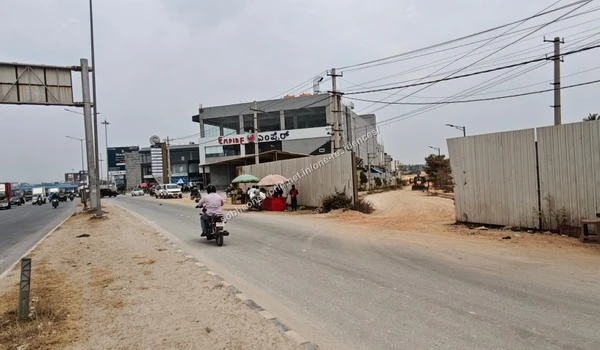 A view of the main road with a two-wheeler passing by the entry path to Sobha One Residences