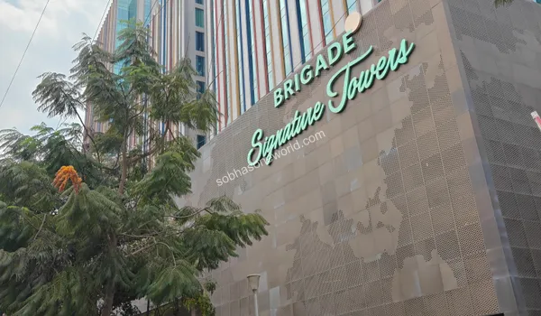 Sweeping view of the grand business park entryway featuring geometric glass designs and vast road connectivity near Sobha One World